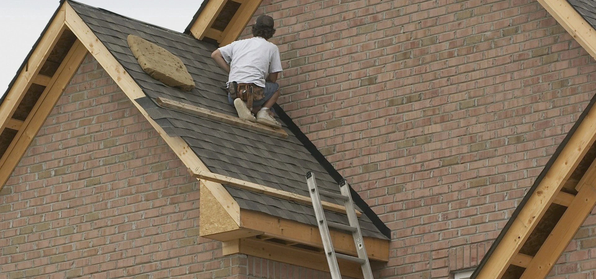 Montaż pokrycia dachowego podczas prac dekarskich na budynku z cegły